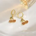 Detail view of gold cherry hoop earrings with sparkling orange and green zircons on white plate - Zirconia Cherry Hoop Style (EH0109)