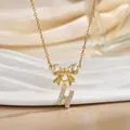 Close-up of golden bow necklace featuring a sparkling zircon-encrusted letter H pendant - Letter H
