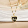 Macro detail of heart-shaped black enamel Fé pendant with golden chain on white ceramic plate - Gold Heart Black Enamel Letter (XL1105A)