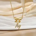 Detailed macro of gold bow necklace with micro-pave zircon letter M pendant charm - Letter M