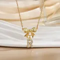 Macro shot of gold bow necklace with letter R pendant inlaid with zircon crystals - Letter R
