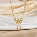 Close-up of golden bow necklace with crystal-paved letter U pendant on silk background - Letter U