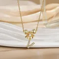 Macro shot of gold bow necklace with letter L pendant and cubic zirconia details - Letter V