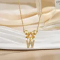Close-up of golden bow and zircon inlaid letter W pendant necklace on velvet display - Letter W