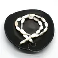 Oval natural freshwater white shell beads for DIY jewelry making on a black plate - Marquise