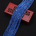 Primer plano de cuentas de turquesa azul oscuro facetadas sobre un joyero de madera - Azul marino