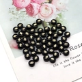 Macro shot of circular black freshwater shell beads with gold Hamsa Hand patterns for DIY jewelry - Palm Hamsa Pattern / 8mm 20 Pieces Per Pack