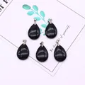 Detailed macro view of teardrop shaped natural stone pendants with cat-eye effect and silver clips - 18x25mm / Black Agate