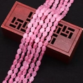 Macro-opname van ovale roze kattenoog kralen op donker hout voor DIY-sieraden - Roze