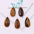 Detailed view of faceted tiger eye stones in teardrop shape with natural brown textures - 13x25mm / Tiger's Eye