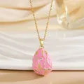 Detailed close-up of pink enamel egg pendant necklace with gold patterns and crystals - Pink