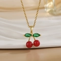 Elegant gold cherry pendant necklace with red round beads and green marquise leaves on a tray - Red Beaded Cherry Style (XL01173)