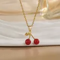 Détail d'un collier pendentif cerise rouge avec feuille dorée sur plateau céramique - Style Cerise Perle Rouge et Feuille d'Or (XL01175) / Or