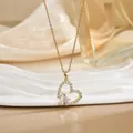 Macro detail of a heart-shaped gold pendant necklace featuring a pink center diamond - Gold Hollow Double Heart Rhinestone Style (XL01617)