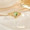 Macro d'une bague coeur en or avec pierre verte et détails pavés sur fond de soie - Style Cœur Couronne Vert (JZ0139F)