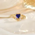 Détail macro d'une bague dorée vintage avec pierre cœur bleue et pétales de zircon - Style Cœur Bleu (JZ0139H)