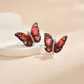 Vue macro de boucles d'oreilles papillon rouges avec corps en diamant sur support beige - Style de Papillon Tacheté Noir Rouge Vif (EH0114GA)