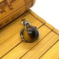 Close-up of a spherical tiger eye stone pendant with silver claw setting and bail - 19x28mm / Tiger's Eye