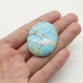 Gros plan d'un cabochon ovale en jaspe bleu de 33x40mm tenu à la main par une personne - Cabochon Ovale (33x40mm, 14g) / Bleu lac