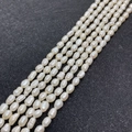 Detailed macro view of 5-6mm natural freshwater rice pearls on a textured black display board - 4-5mm (10g) / White