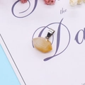 Faceted yellow quartz stone pendant with silver clasp on a decorative background - 12x17mm / Topaz
