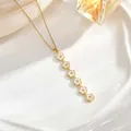 Detail of long gold chain necklace featuring cascading white enamel flowers on ceramic tray - Six White Enamel Flower Style (XL01930)