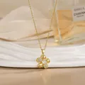 Close-up of a rotating gold flower pendant necklace with crystals on white tray - Pave Five-Petal Floral Style (XL02179)