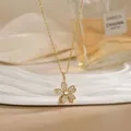 Close-up of rotatable 18K gold flower necklace with zircon inlay on a white ceramic plate - Six-Petal Floral Pave Style (XL02187)