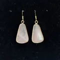 Detail view of pink quartz drop earrings with gold-plated bezel on black jewelry stand - 16x30mm / Pink