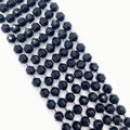 Macro detail of faceted black natural stone beads with polished diamond cut surfaces - Black Agate