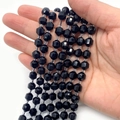 Strand of multifaceted black onyx beads for DIY jewelry making held in hand - Blue Sandstone