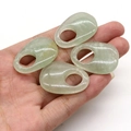 Close-up of four natural green moss agate oval pendants with large holes held in hand - Green Aventurine