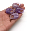 Close-up of four natural polished purple amethyst oval pendants held in a person's hand - Purple Crystal