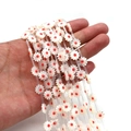White and red daisy sea shell beads for DIY jewelry making shown on hand - Red Heart (No. 5)