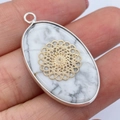 Ovale witte turkoois hanger met gouden mandala inleg en een zilveren rand in hand - Witte Turkoois Bloemenpatroon