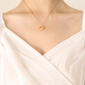 Golden pig pendant necklace with red heart detail worn by a model on a white top - 40+5cm