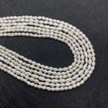 Macro shot of 3-4mm white freshwater baroque pearls showing natural luster on dark surface - Grade A Style / 7-8mm
