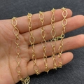 Golden textured oval link chain for DIY jewelry making held by hand to show detail - 6x9mm (10m/Roll)