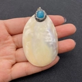 Irregulärer weißer Muschelanhänger mit blauem Edelstein und Diamanten in der Hand - Blauer Edelstein (4883421241969) / Blau