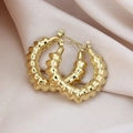 Vue détaillée de créoles dorées texture bambou sur un tissu de soie doux couleur champagne - Style Bambou Texturé / Pack de 1 paire / Or