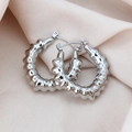 Vue macro de boucles d'oreilles créoles en acier titane argenté sur tissu de soie - Style Bambou Texturé / Pack de 1 paire / Acier