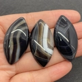 Trois agates polies en forme de marquise tenues dans la paume pour montrer la taille - N°4 (Agate Rubanée Noir Blanc)