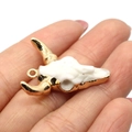 Natural resin bull head pendant with gold plating on hand for scale reference - 27x31mm / US 8