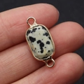 Hand holding a rectangular dalmatian jasper stone pendant with gold dual rings - 10x24mm / Dalmatian Jasper