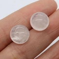 Natural round rose quartz cabochon stud earrings held by hand to show 12mm size - White Crystal