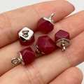 Faceted red gemstone pendants with silver caps held in hand to show the small 8x11mm size - Red Stone