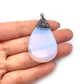 Handheld view of a teardrop-shaped opal pendant with a crystal-encrusted pave bail - Opal