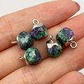 Five Ruby Zoisite faceted stone pendants with silver metal bails on a hand background - Ruby Zoisite