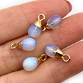 Four light blue teardrop stone pendants with gold caps held on fingertips for DIY jewelry - Opal Style (5037910906843)