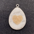 Macro detail of teardrop white marble stone pendant with a gold hollow heart motif - Heart